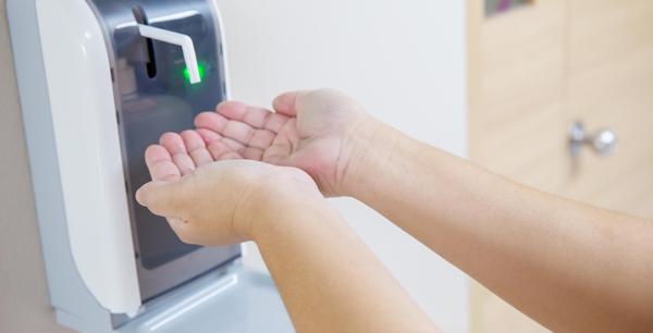hands under the sanitizer dispenser