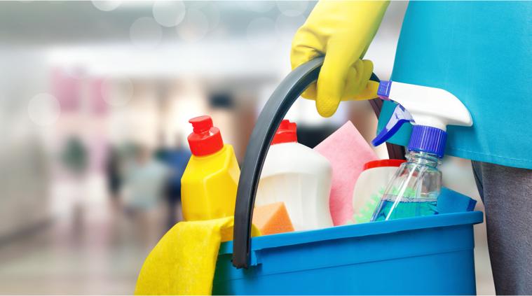 A janitor holding a plastic bucket with cleaning supplies